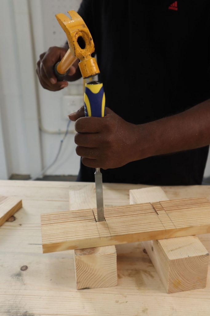 using chisel to take out the wood from the slot