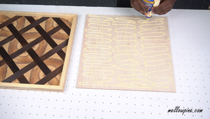 Applying wood glue to the plywood base for fixing the wall art on it