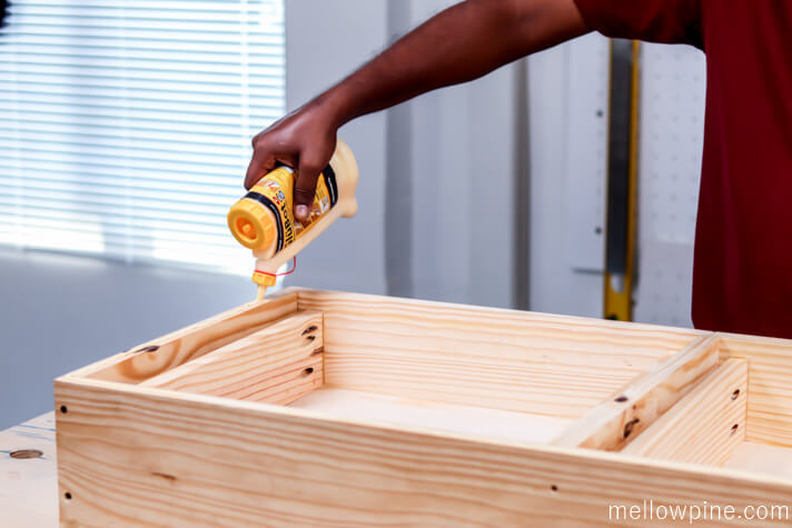 applying glue on the top edges of the desk for fixing the top panel