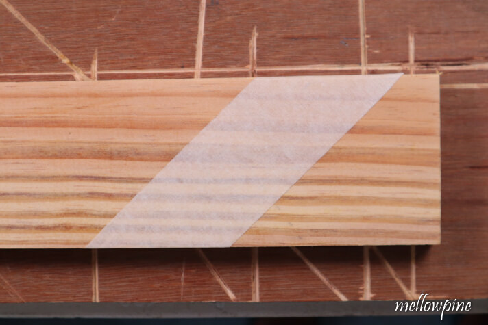 fixing masking tape on the wood to be cut