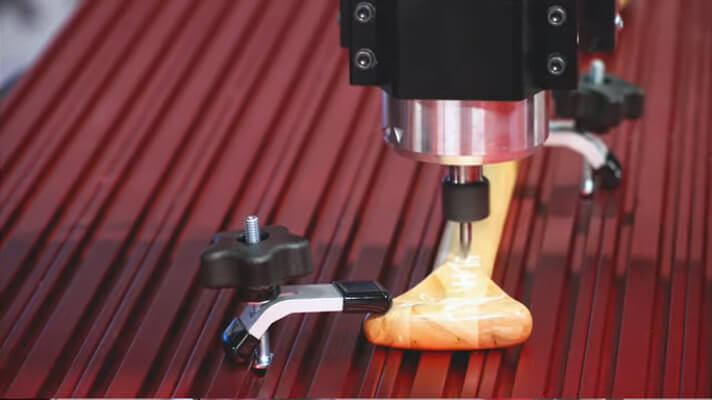 A wooden piece clapped onto the workbed of a CNC router 