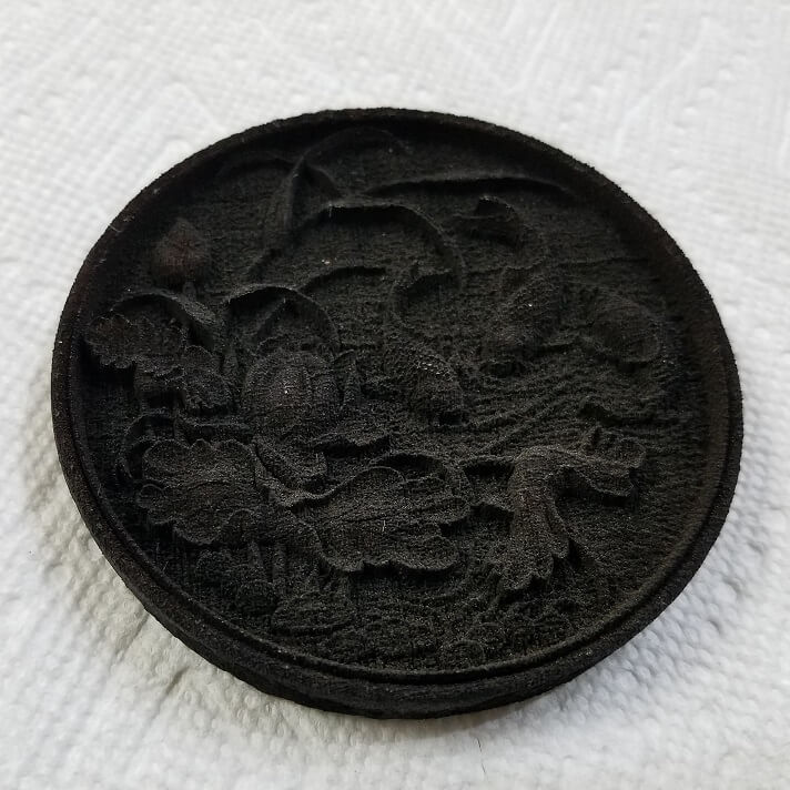 A design 3D laser engraved on a piece of walnut wood straight off of the laser