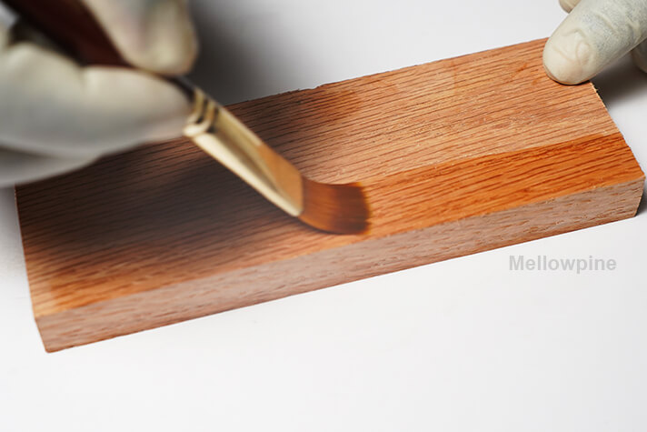 Using a brush to apply tung oil on oak workpiece 